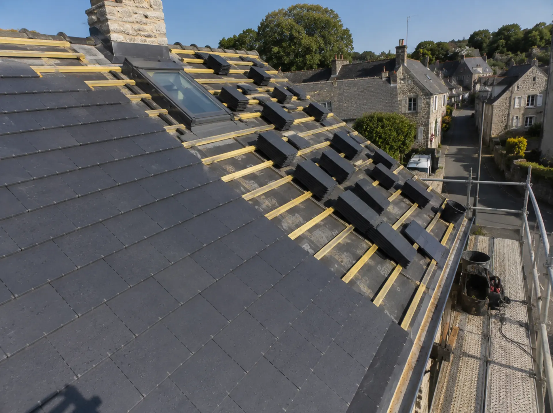 Travaux de toiture à Saint-Herblain : versant en ardoises avec fenêtre de toit et paquets d'ardoises répartis sur le liteaunage